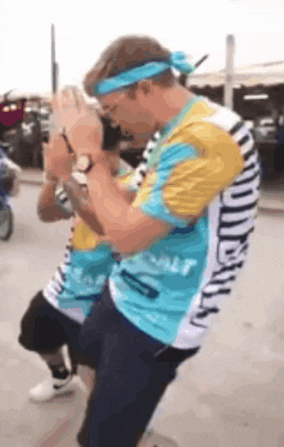 a man wearing a blue headband is standing next to another man wearing a striped shirt that says ' miami '