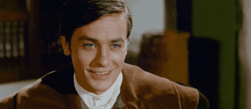 a man with blue eyes is smiling and wearing a brown jacket and white shirt .