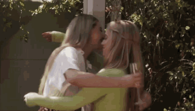 two women are hugging each other with one holding a glass of wine