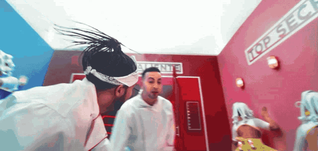 two men are dancing in a room with the word top secret on the wall