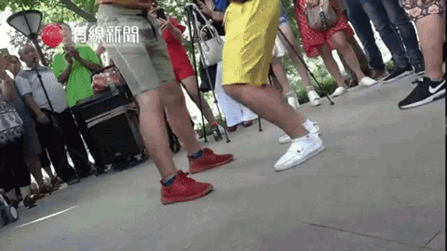 a group of people standing on a sidewalk with chinese writing on the bottom