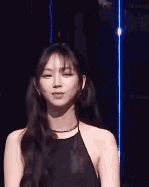 a woman with long hair is wearing a black halter top and a necklace .