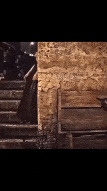 a person is walking up a set of stairs next to a brick wall