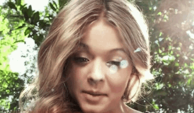 a close up of a woman 's face with a butterfly on her eye .