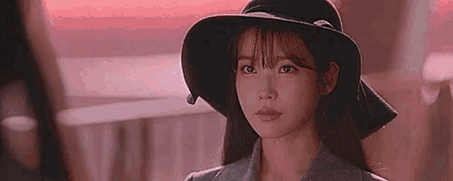 a woman wearing a hat and a suit is standing in front of a table .