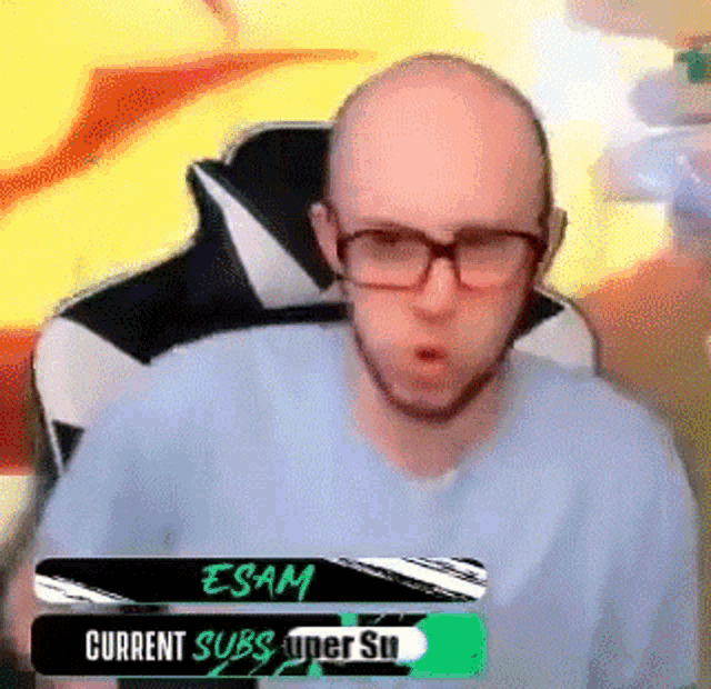 a bald man wearing glasses and a blue shirt is sitting in a chair with his mouth open .