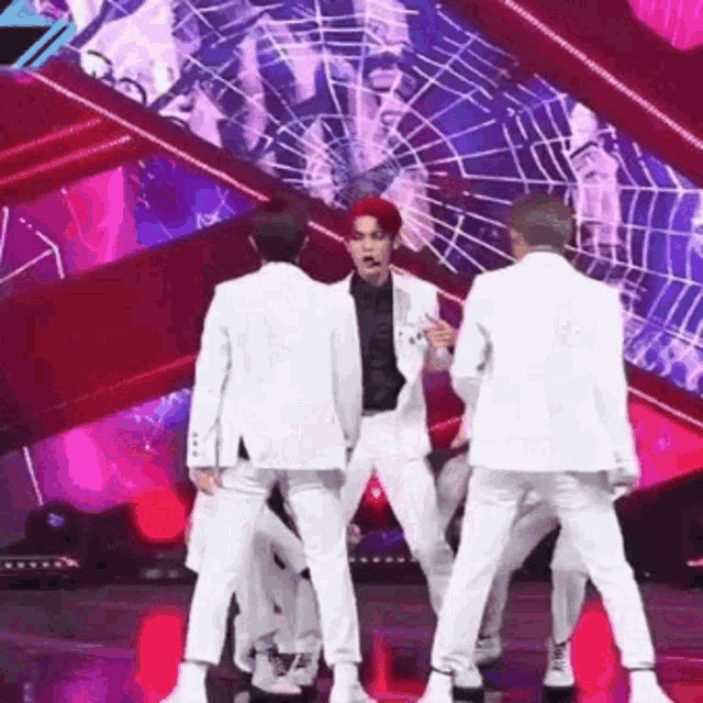 a group of men are dancing on a stage in front of a spider web .