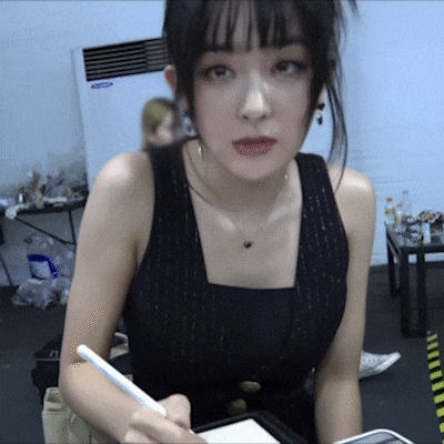 a woman in a black vest is holding a pen in her hand .