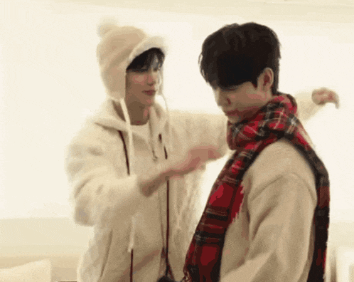 a man is putting a scarf on another man 's head