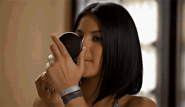 a woman is applying makeup in front of a mirror that says mac on it