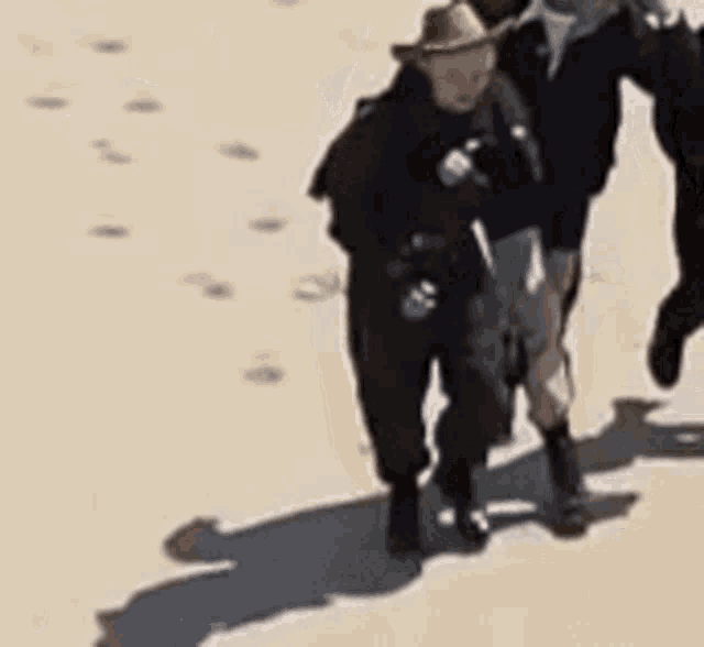 a man in a cowboy hat is running with another man .