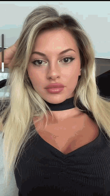 a woman with blonde hair and a choker around her neck looks at the camera