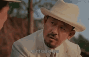 a man in a suit and hat is talking to another man in chinese