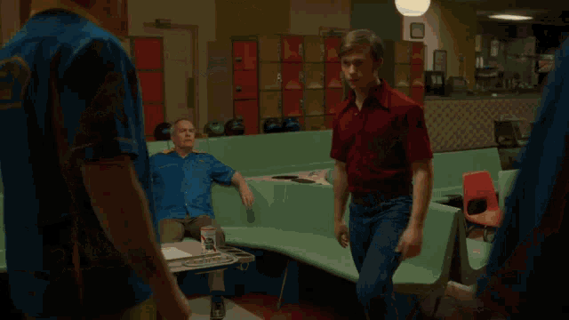 two men are playing bowling in a bowling alley and one is holding a bowling ball .