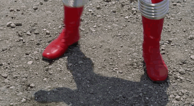 a person wearing red boots is standing on a dirt road