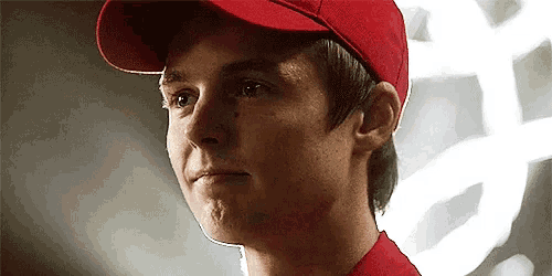 a young man wearing a red hat and a red shirt is looking at the camera .