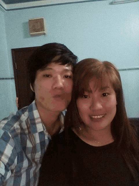 a man and a woman are posing for a picture with a clock on the wall behind them