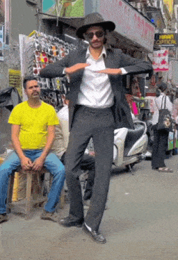 a man in a suit and hat is dancing in front of a store called bengal sports