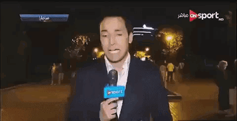 a man is holding a microphone in front of a screen that says " on sport "