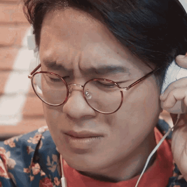 a man wearing glasses and headphones is making a sad face