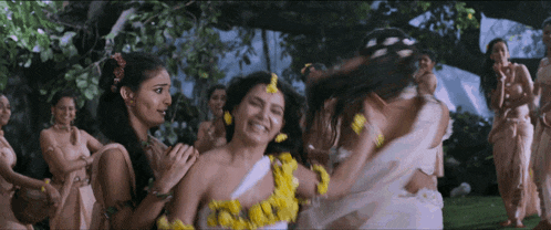 a group of women are standing in a field and one of them is wearing yellow flowers in her hair