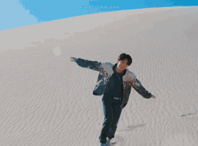 a man in a black shirt is smiling in front of a sand dune with the words minieggookie.gifs written on the bottom