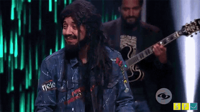 a man with long hair and a beard is wearing a blue jacket that says melo