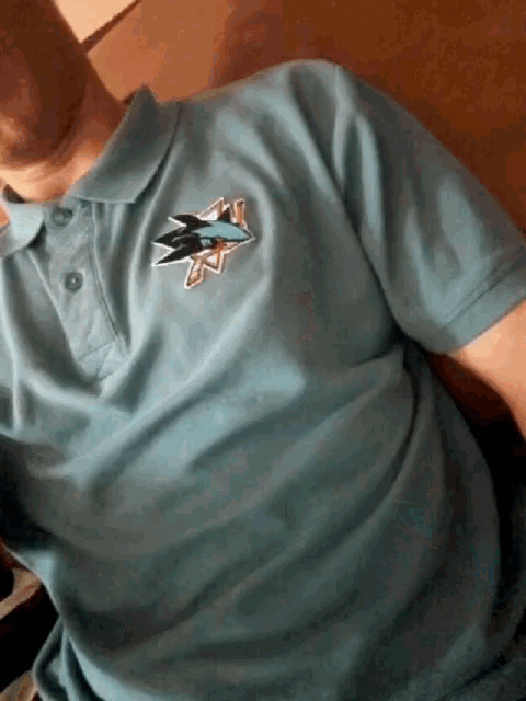 a man is wearing a polo shirt with a shark logo on it