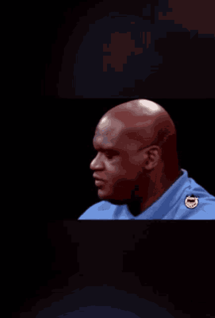 a bald man in a blue shirt has a badge on his shoulder