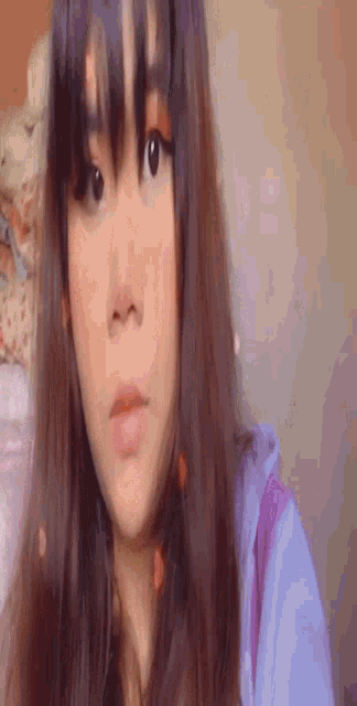 a close up of a woman 's face with long hair and a purple shirt .