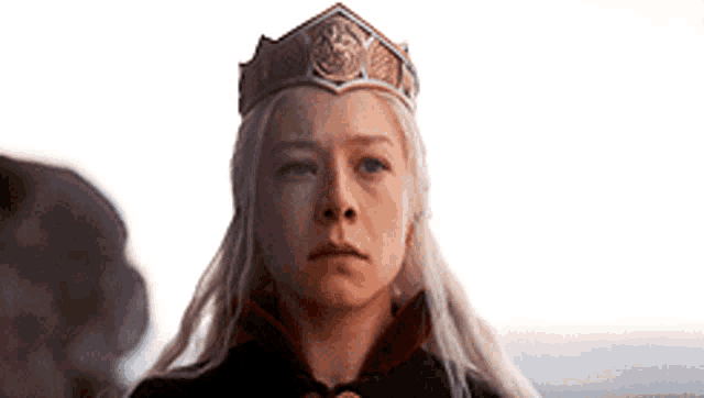 a woman with long white hair is wearing a crown and a cape .
