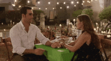 a man and woman are holding hands at a table