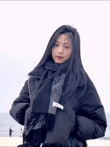 a woman wearing a black jacket and a scarf with the word louis on it