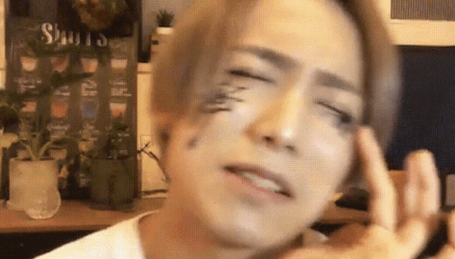 a young man with a tattoo on his face is making a face .
