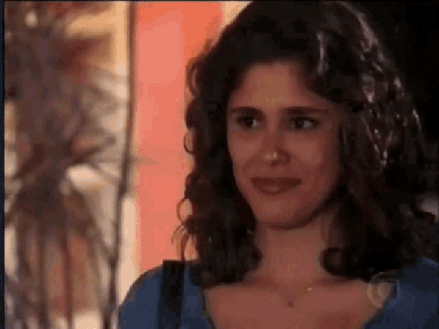 a woman is smiling and looking at the camera while wearing a blue shirt .