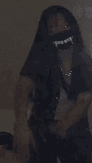 a woman wearing a mask with vampire teeth on it is taking a selfie in the dark .