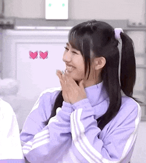 a girl in a purple jacket with white stripes is smiling and holding her hands to her face .