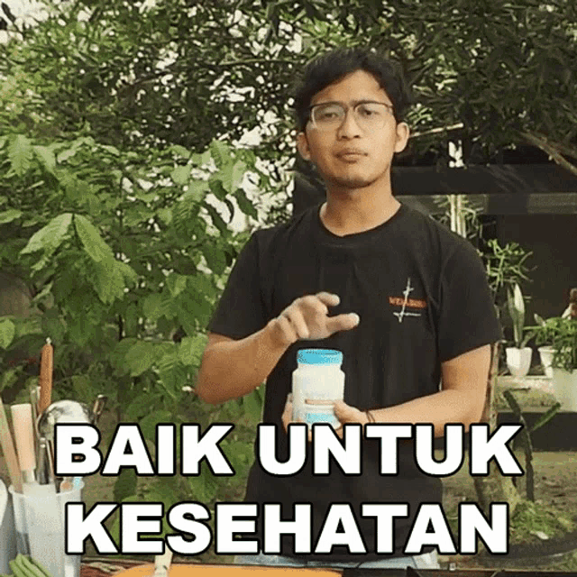 a man in a black shirt is holding a bottle that says baik untuk kesehatan on it