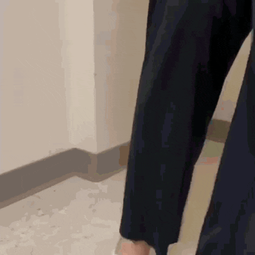a person in a suit is walking down a hallway with their arms outstretched .