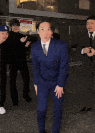 a man in a blue suit is dancing with his hands in the air