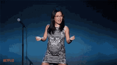 a pregnant woman in a striped dress is standing in front of a microphone .