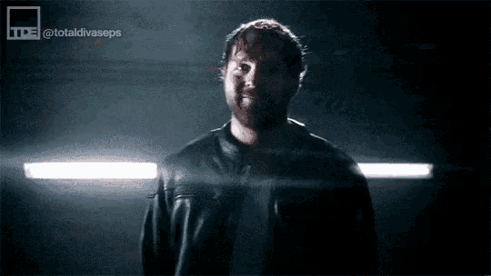 a man in a leather jacket is standing in the dark .