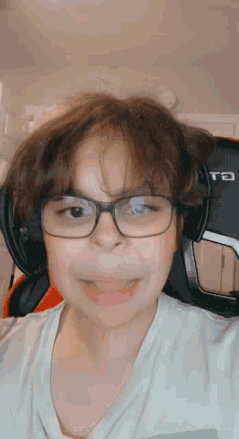 a young boy wearing glasses and headphones is making a funny face .