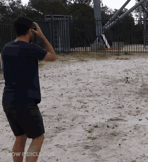 a man in a blue shirt is standing on a sandy beach with the words how ridiculous below him
