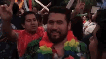 a man with a beard is wearing a lei around his neck while dancing at a party .
