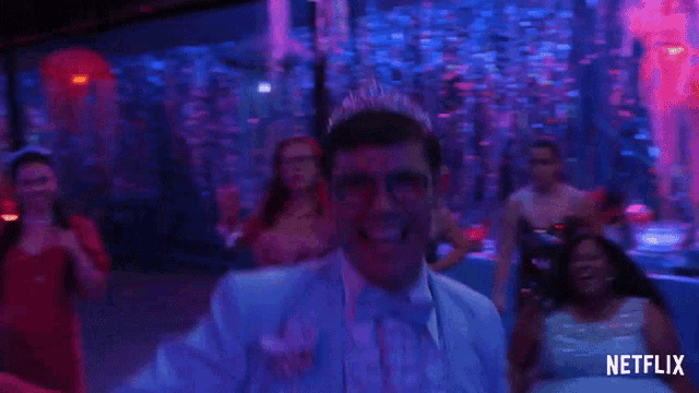 a man in a tuxedo with a tiara on his head is dancing in front of a netflix sign