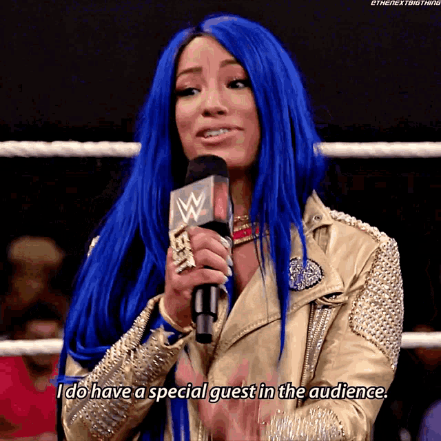 a woman with blue hair is talking into a microphone and says i do have a special guest in the audience