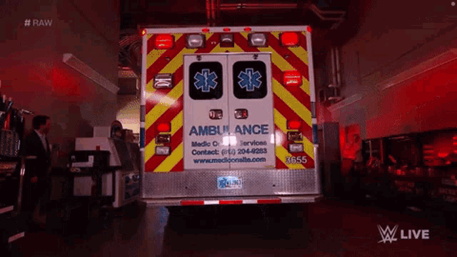an ambulance is parked in a dark room with a man in a suit standing next to it