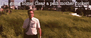 a man in a white shirt and tie stands in a field with the words i 'm going home clear a path mother fucker