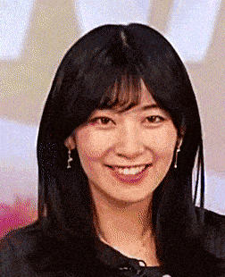 a woman with long black hair is smiling and wearing earrings